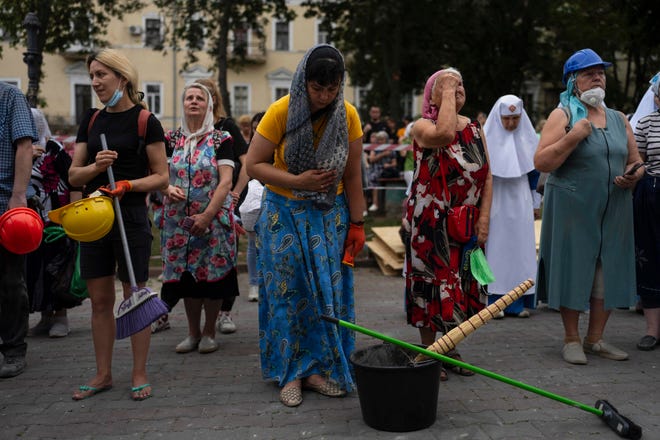 People attend a Mass outside the Odesa Transfiguration Cathedral after helping clean up the church in Odesa, Ukraine, on Sunday.