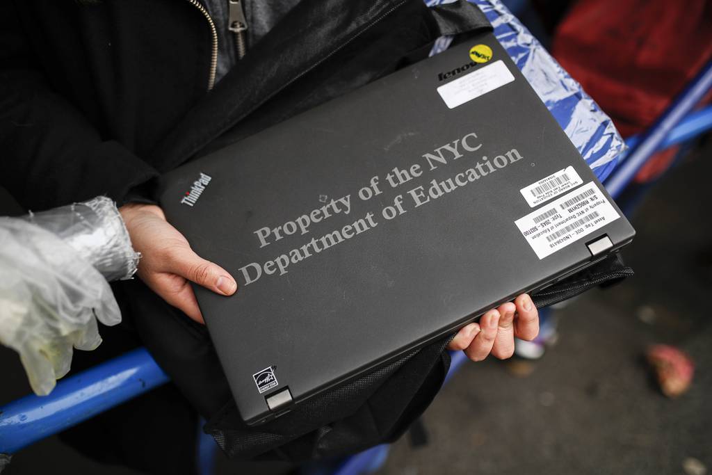 A student receives her school laptop for home study at the Lower East Side Preparatory School Thursday, March 19, 2020, in New York.