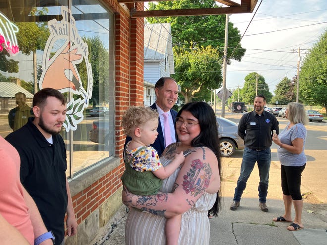 Rebekah Elliott holds her 17-month-old daughter, Nora, at the ribbon-cutting for her new business, the Nail Nook, on Friday morning. Shelby Mayor Steve Schag is in the background.
