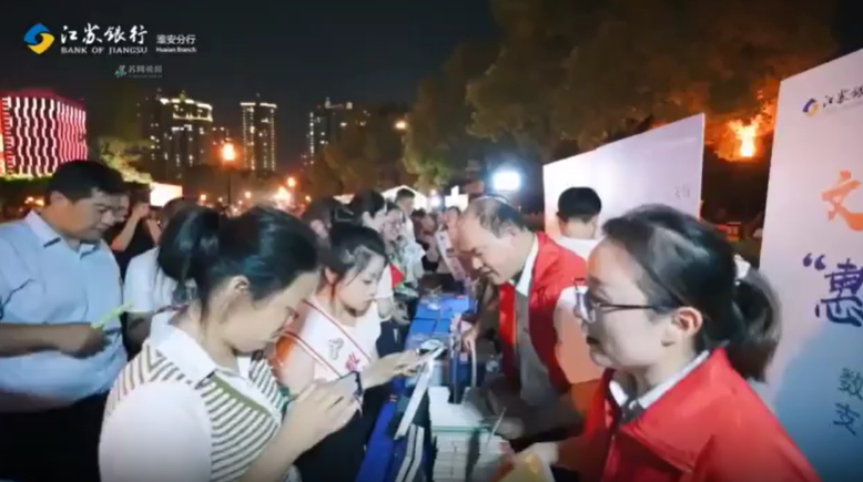 Bank of Jiangsu staffers show citizens in Huai'an, China, how to use the e-CNY.