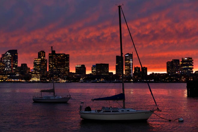 The sun sets behind the city skyline in advance of Hurricane Lee, Friday, Sept. 15, 2023, in Boston.
