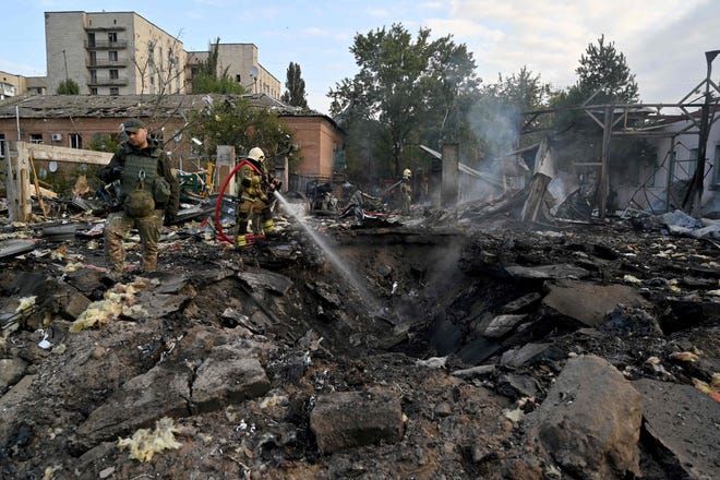 Firefighters put out a blaze as police experts look for fragments of a missile in an industrial area of the Ukrainian capital of Kyiv on Sept. 21, 2023.