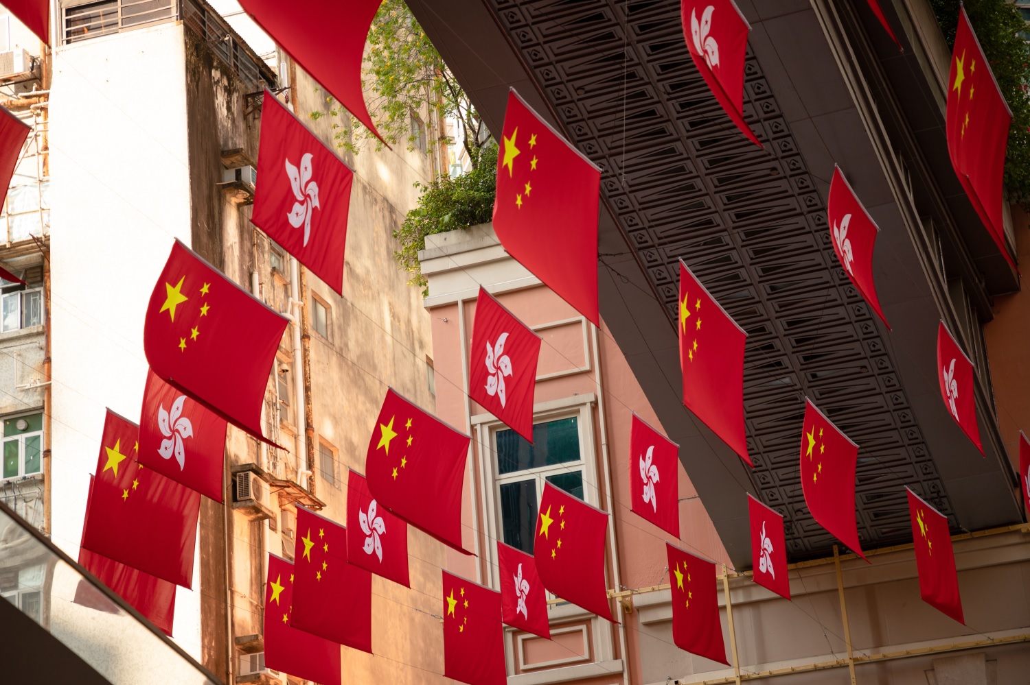 Flags of the PeopleÔÇÖs Republic and Hong Kong hang in a public street.