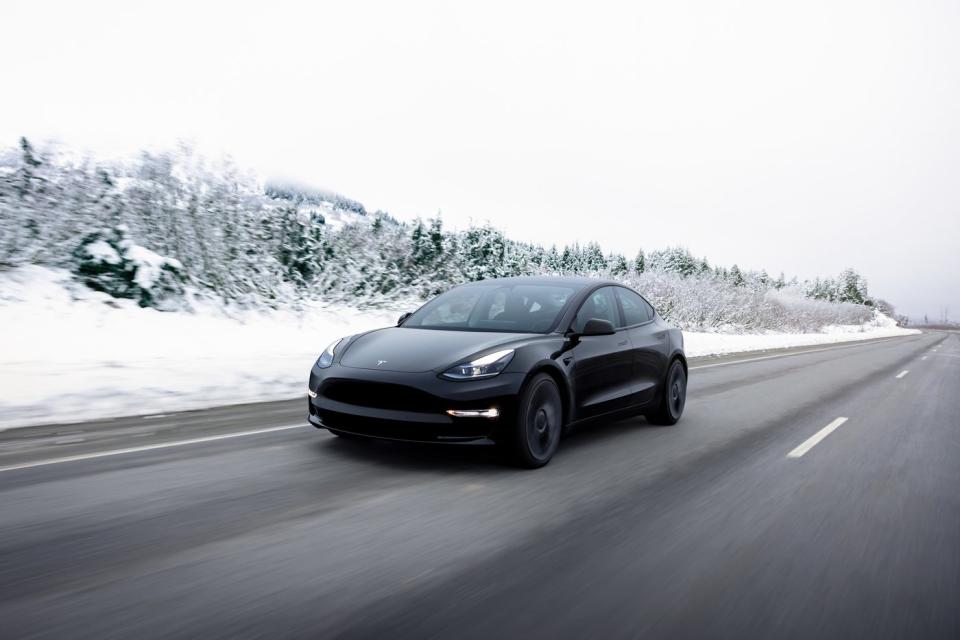A Tesla Model 3 driving down a snowy road.